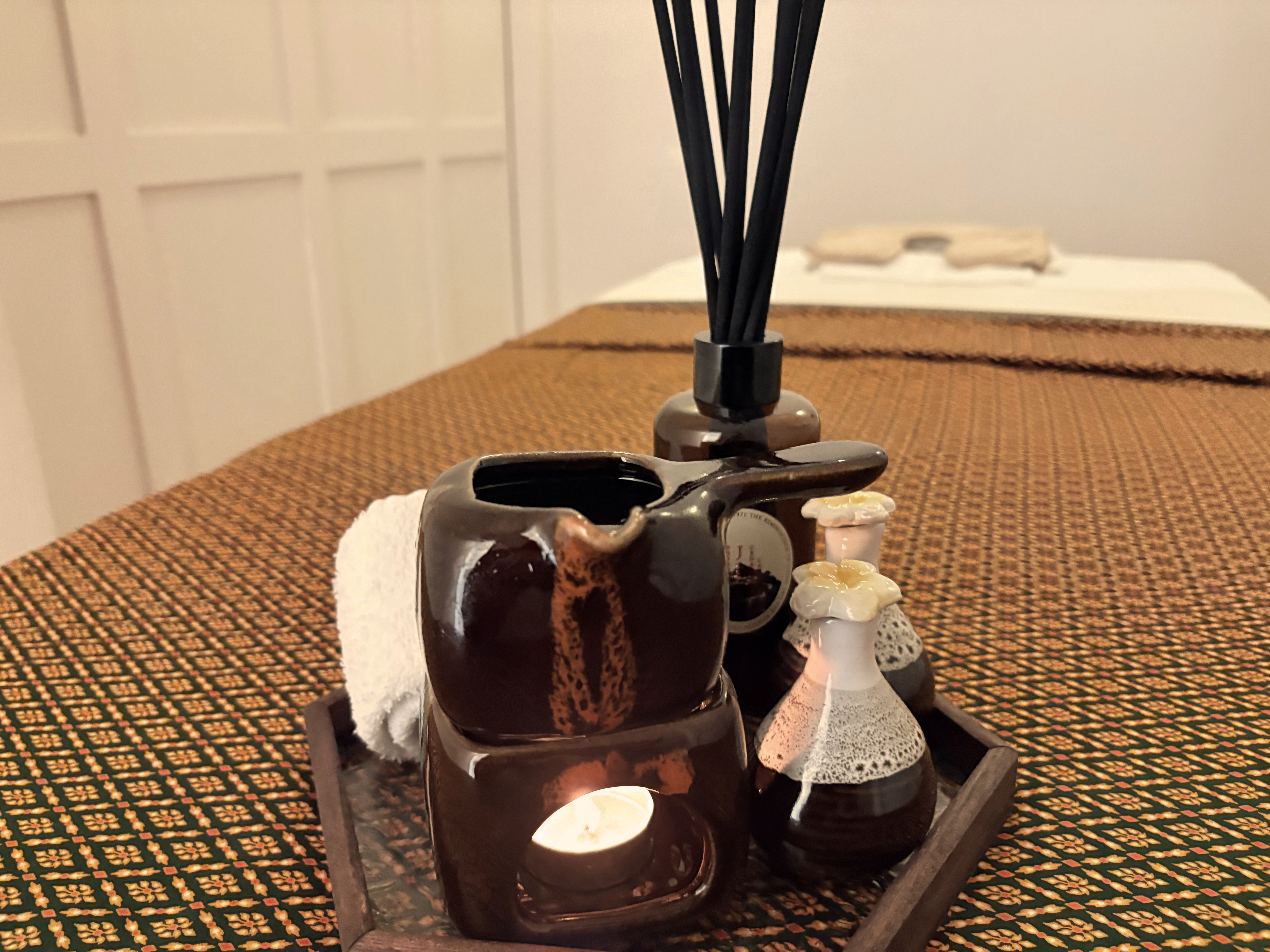 Aromatherapy oils and reed diffuser on traditional Thai mat in Siam Soul treatment room, Orakei Auckland